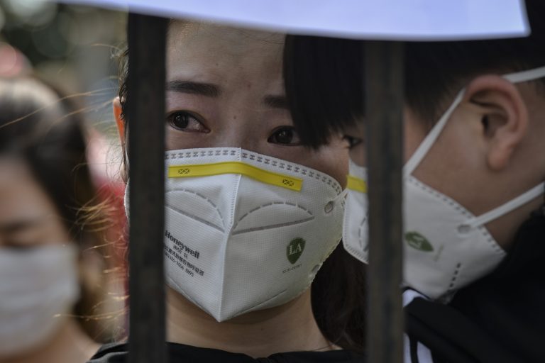 This photo taken on March 18, 2020 shows a resident reacting as members of a medical assistance team from Yunnan province depart after helping with the COVID-19 coronavirus recovery effort in Wuhan, in China's central Hubei province. (Image: STR/AFP via Getty Images)
