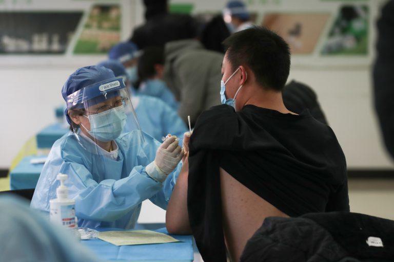 A medical worker (L) administers a Covid-19 coronavirus vaccine to a man at a temporary vaccination center in Beijing on January 8, 2021. (Image: STR/CNS/AFP via Getty Images)