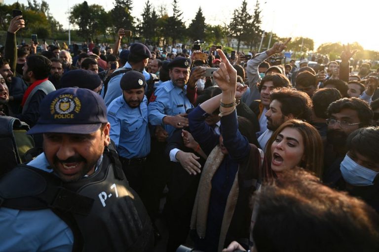 Policemen stand in the middle as activists (L) of the ruling party Pakistan Tehreek Insaf (PTI) and supporters (R) of opposition coalition of the Pakistan Democratic Movement (PDM) party confront during the Pakistan Senate election, outside the Senate building in Islamabad on March 12, 2021.