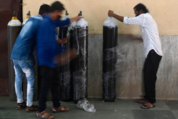 Staff unwrap oxygen cylinders at a newly set up Covid-19 care centre in Mumbai on April 26, 2021. Some speculate an increase in deaths has been caused by a lack of oxygen rather than death from the pathogenicity of the virus itself. (Image: INDRANIL MUKHERJEE/AFP via Getty Images)