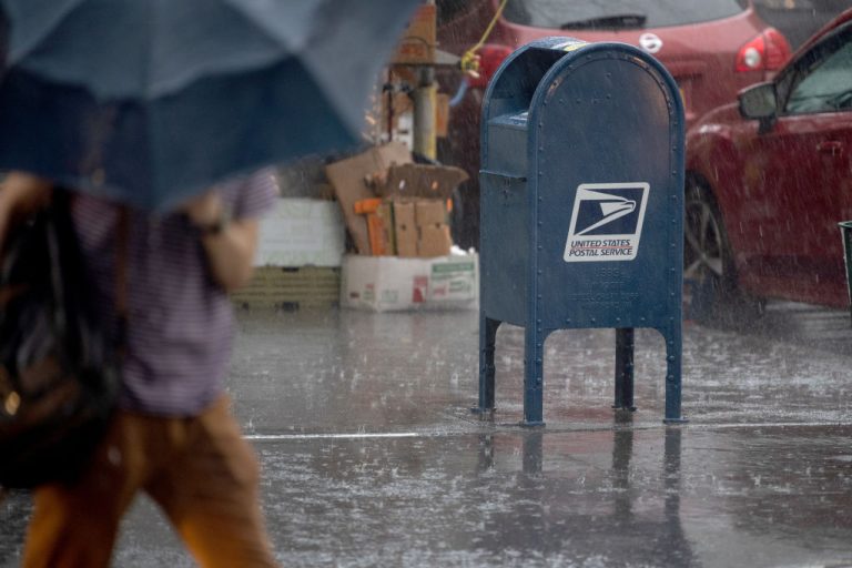 A person carrying an umbrella walks past a USPS mail box in the rain on August 25, 2020 in New York City. A team of the Postal Service’s law enforcement arm specializing in covert internet operations has been found surveilling social media and communication platforms such as Telegram and Parler for right-wing content.