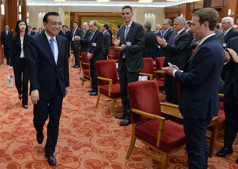 Facebook CEO Mark Zuckerberg (R) and the overseas representatives of the China Development Forum applaud as Chinese Premier Li Keqiang arrives for a meeting in Beijing on March 21, 2016. ‘Zuck’ has been selling his company’s influence on the world’s people to the Chinese Communist Party so it can whitewash and astroturf about the genocide of Uyghur Muslims in the Xinjiang Autonomous Zone.