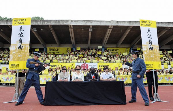 Amnesty International members perform an interpretation of censorship against journalists by gagging and surrounding supposed journalists by mock police on May 31, 2008 in Paris during the event "An arena for human rights in China", ahead of this summer's Olympic games in Beijing. 
