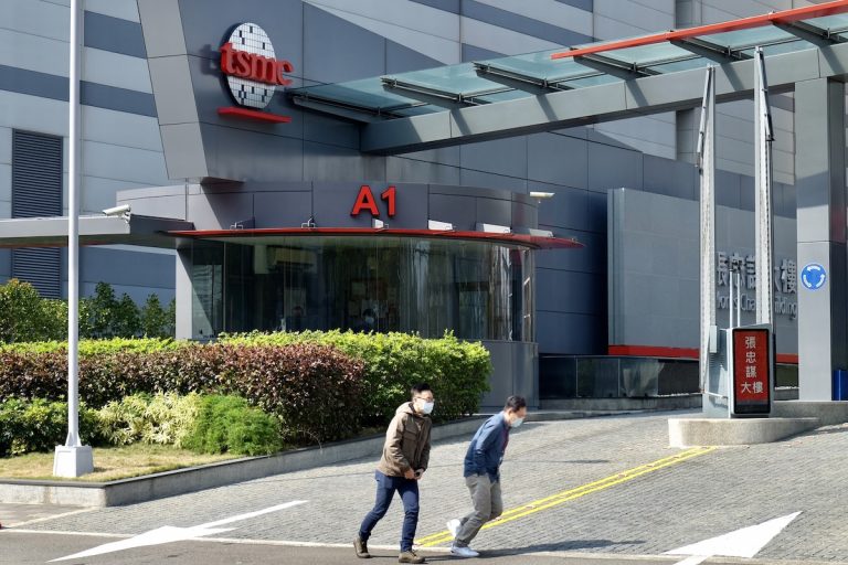 People walk past the headquarters of the world's largest semiconductor maker TSMC in Hsinchu on January 29, 2021.