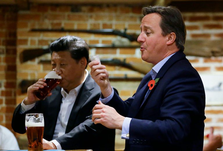 Ex-British Prime Minister David Cameron gets out money to pay for drinks as China's President Xi Jinping drinks a pint of beer during a visit to the The Plough pub on October 22, 2015 in Princes Risborough, England. The Plough’s owner, Greene King, is now in the hands of Hong Kong billionaire Li Ka Shing as part of an unhealthy trend of British businesses selling out to the Communist Party.
