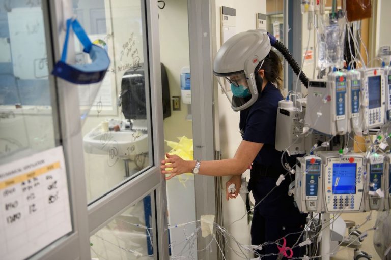 A nurse wearing personal protective equipment (PPE) including a personal air purifying respirator (PAPR) closes a door to a patients room in a Covid-19 intensive care unit (ICU) at Martin Luther King Jr. (MLK) Community Hospital on January 6, 2021 in the Willowbrook neighborhood of Los Angeles, California.