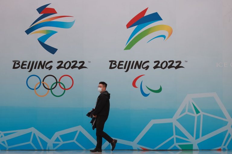 Cittadino cinese indossa una mascherina mentre cammina davanti ai loghi delle Olimpiadi invernali di Pechino 2022 al National Aquatics Centre il 9 aprile 2021 a Pechino, in Cina. (Immagine: Lintao Zhang tramite Getty Images)