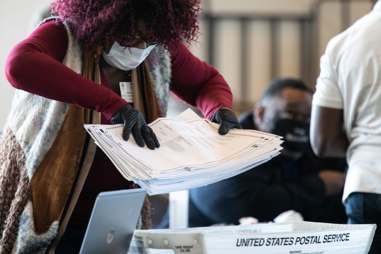 A Fulton county worker moves a stack of absentee ballots at State Farm Arena on November 6, 2020 in Atlanta, Georgia.