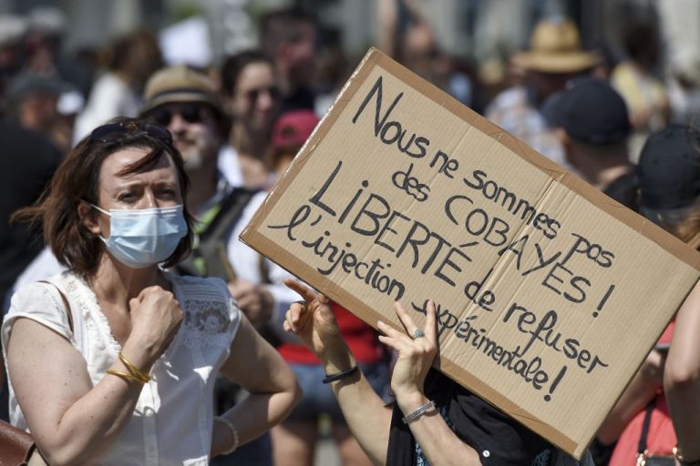 A woman holds a placard reading "We are not laboratory subjects! Freedom to refuse experimental injection"during a demonstration against the Macron administration’s use of mandatory vaccine passports, which come with jail time for businesses and individuals who circumvent them, to erode the nation’s vaccine hesitancy in Nantes, western France, on July 17, 2021.