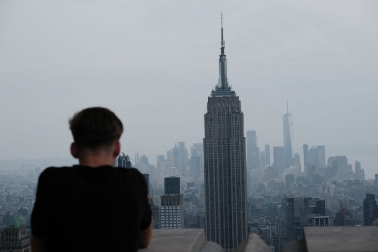 People view the Manhattan skyline as it continues to sit under a haze on July 21, 2021 in New York City. According to data from the National Oceanic and Atmospheric Administration, wildfire smoke from the west has arrived in the tri-state area creating decreased visibility and a yellowish haze in many areas.