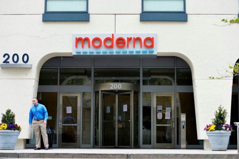 A man stands outside Moderna headquarters in Cambridge, Massachusetts on May 18, 2020. The company announced it is working on 37 Messenger RNA (mRNA) products, including an influenza vaccine, a hybrid COVID-19/influenza booster, a cancer vaccine, and a “next-generation” COVID-19 injection.
