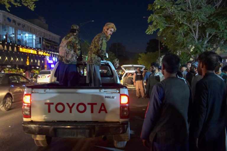 Taliban fighters stand on a pickup truck outside a hospital as volunteers bring injured people for treatment after two powerful explosions outside the airport in Kabul on August 26, 2021.
