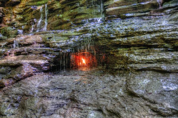 Behind a waterfall at the Shale Creek Preserve, which is part of the Chestnut Ridge Park in Orchard Park, NY, is a small cave where a crack in the shale emits methane gas -- which is alight. The Eternal Flame Waterfall. 