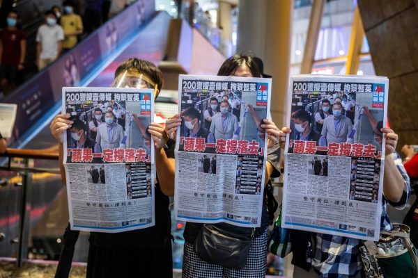People hold up copies of Apple Daily as they protest for press freedom inside a mall in Hong Kong on August 11, 2020, a day after authorities conducted a search of the newspaper's headquarters following the arrest of founder Jimmy Lai under the new National Security Law. Hong Kongers rushed to buy pro-democracy newspaper Apple Daily on August 11 in a show of support for its owner, who was arrested a day earlier as police rounded up critics of China. 