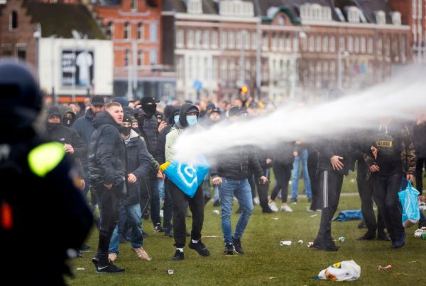 Demonstrators are sprayed by a police water cannon at Amsterdam's Museumplein during a protest against lockdowns on January 21, 2021.