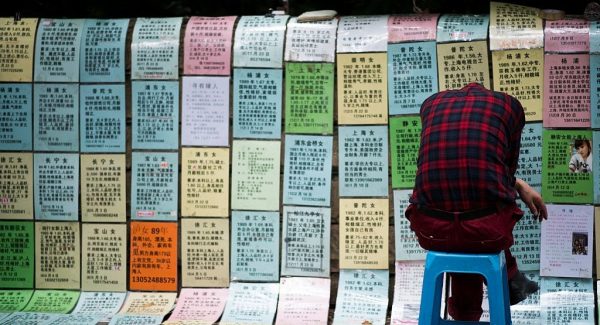 A Chinese man sleeps in front of advertising notices, placed there by parents, of people looking for partners at a marriage market in Shanghai on May 30, 2015. China's One-Child Policy has created a severe gender imbalance and many other problems for the future of the country. 