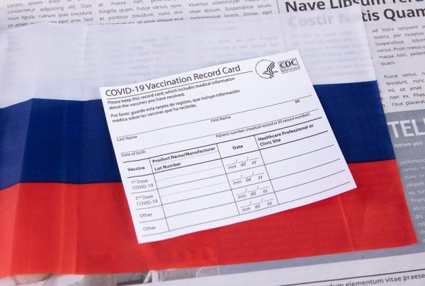 U.S. Centers for Disease Control paper COVID-19 Vaccination Record Card laid atop a Russian flag in a stock photo. Russia’s Foreign Minister Sergey Lavrov wore a mask with the words “FCKNG QRNTN” during his March 22 trip to China. The Russian Foreign Ministry said “Both the mask and the slogan suited the minister just right.” 