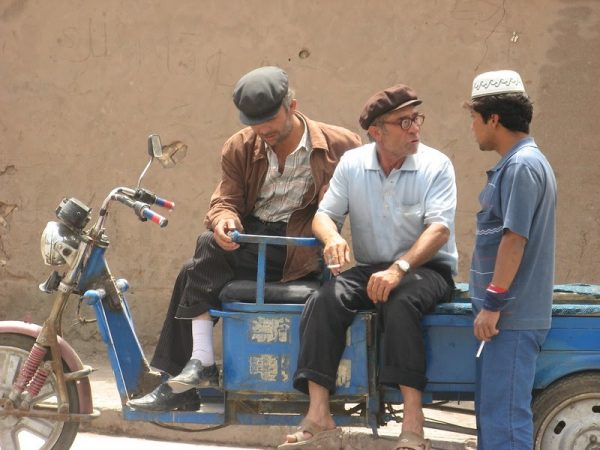 Uighur men chatting with each other in Xinjiang, China. The Chinese regime allegedly tests its newest surveillance technologies on this group and sends dissidents to reeducation camps. 