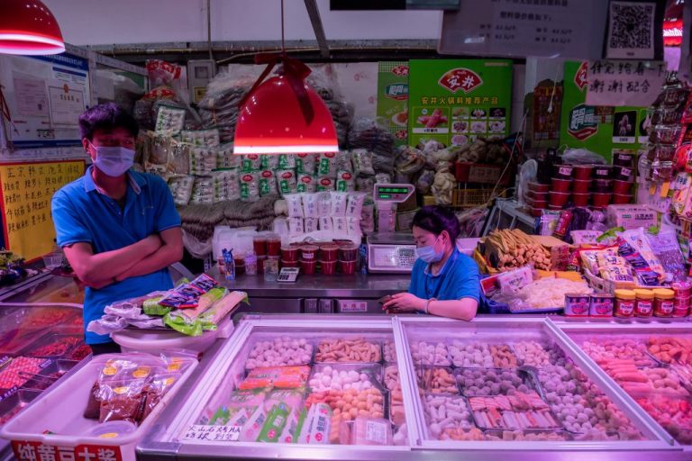 Vendors wait for customers at their stall selling frozen meat and seafood balls at a market.