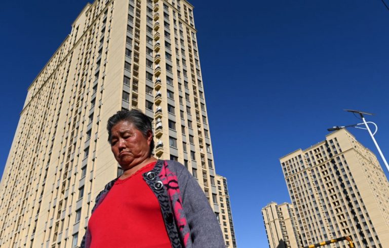 A woman walks in front of a housing complex by Chinese property developer Evergrande in Beijing on October 21, 2021.