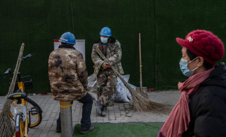 Workers sit outside a construction site in 2021 in Beijing, China.