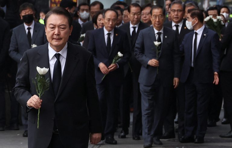 South Korean President Yoon Suk-Yeol holds a flower to be placed as a tribute to victims as he visits the scene of a crowd crush that happened during Halloween festivities, in Seoul, South Korea, November 1, 2022.