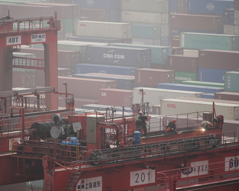 Workers are seen on a crane above containers at the Yangshan Deep Water Port in Shanghai, China January 13, 2022. (Image: Screenshot / REUTERS)