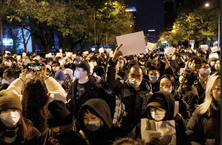 People hold white sheets of paper in protest of coronavirus disease (COVID-19) restrictions, after a vigil for the victims of a fire in Urumqi, as outbreaks of the coronavirus disease continue in Beijing, China, November 27, 2022. (Image: Screenshot / Reuters)