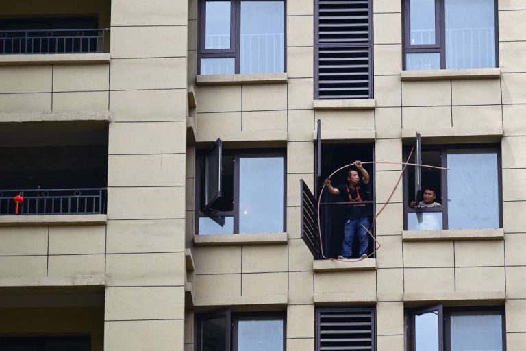 construction-workers-repairing-a-flat-at-a-complex-of-unfinished-apartment-buildings-in-xinzheng-city-in-zhengzhou-china-chinese-economy-slumped-due-to-the-covid-lockdowns-leading-to-a-99-percent-crunch-in-tourists-visiting-china